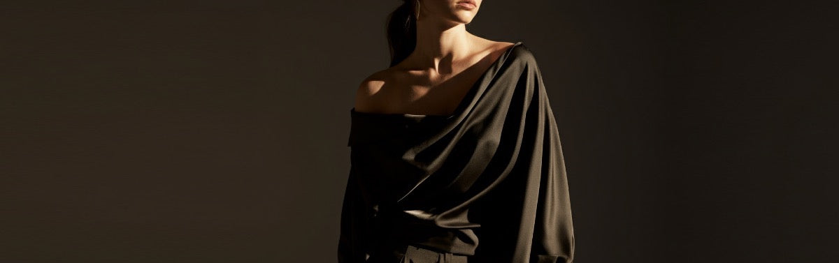 Elegant woman in a minimalist silk shirt and pants, showcasing timeless, understated luxury.